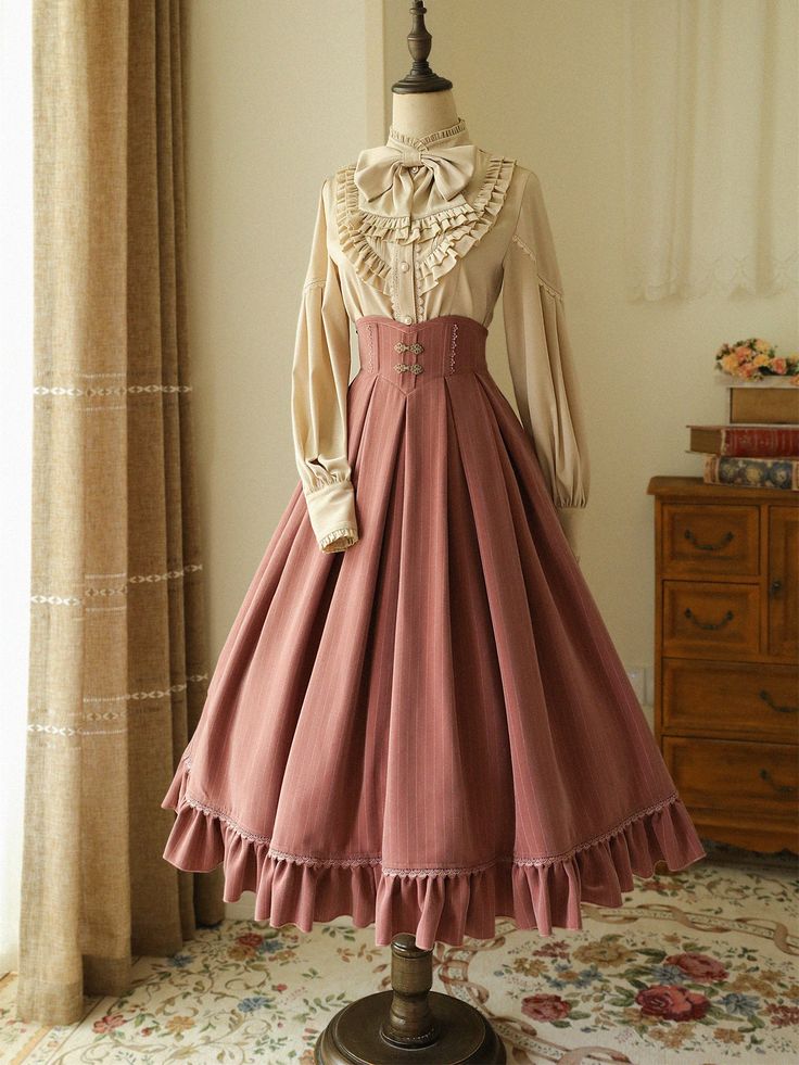 a fulllength view of a mannequin dressed in a vintageinspired outfit. the mannequin stands on a creamcolored carpet in a room with white walls. it wears a flowing, dusty rose skirt with a lace trim, paired with a highwaisted corset.  a creamcolored, longsleeved blouse with ruffles adorns the upper body. a matching bow tie completes the romantic look.  behind the mannequin, a cream curtain hangs to the left, while a wooden dresser adorned with a vase of flowers is positioned to the right. the bright, natural light enhances the soft and elegant feel of the scene.