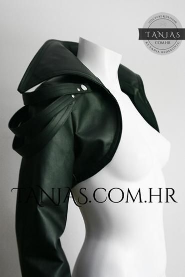 a close up of a woman wearing a black leather crop jacket. she is standing in a studio with a white background, the jacket is  very stylish and elegant, showing off the model's figure and making her look very fashionable.