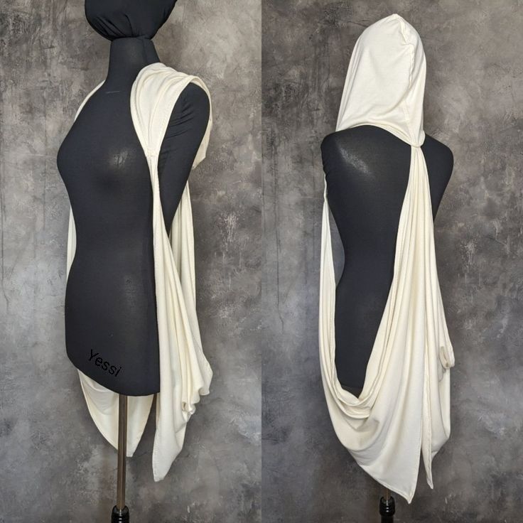 the image features a creamcolored hooded scarf draped on a black mannequin against a grey textured background. the scarf is arranged with a cowl neck in the front and a hood at the back. the fabric drapes elegantly down the sides. the mannequin is labeled "yessi".
