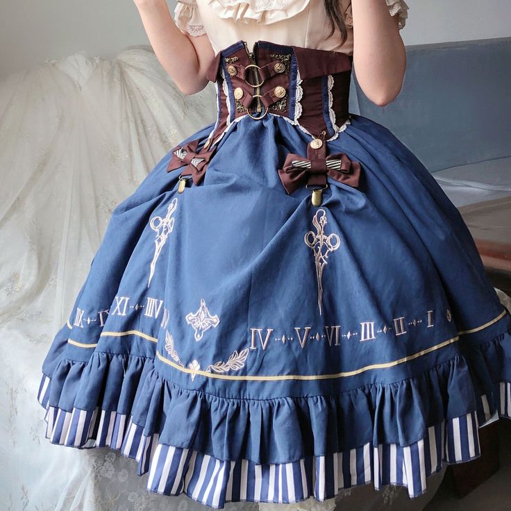 a woman is standing, wearing a blue and white lolita fashion dress with steampunk elements. the dress features a brown corsetstyle waistband, intricate embroidery, and a ruffled skirt. the photo is taken indoors in a bright room with natural light.