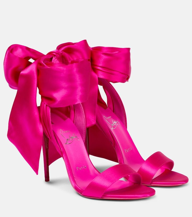 a pair of pink satin high heels with a bow. the heels are very high and the shoes are made of a soft, silky satin. they are perfect for a special occasion or a night out. the shoes are a beautiful and elegant choice for any woman who wants to make a statement.