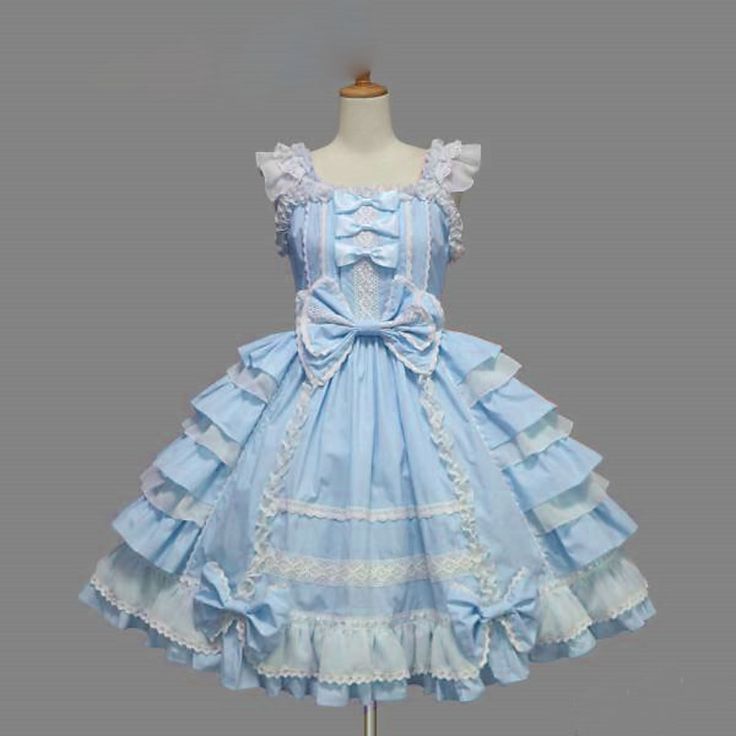 a light blue lolita dress with white lace detailing is shown on a mannequin against a gray background. the dress features a tiered skirt with layers of ruffles and bows, and a fitted bodice with straps and a sweetheart neckline. the bodice is adorned with more lace and bows. the dress gives off a sweet and delicate feel, reflecting the common aesthetics of lolita fashion.