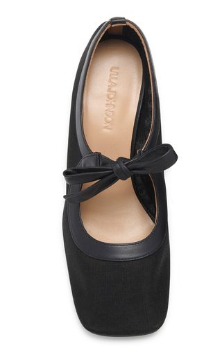 a pair of black women's leather mary jane flats with a bow on the front. the shoes have a classic, elegant look and are perfect for a formal occasion or a night out.