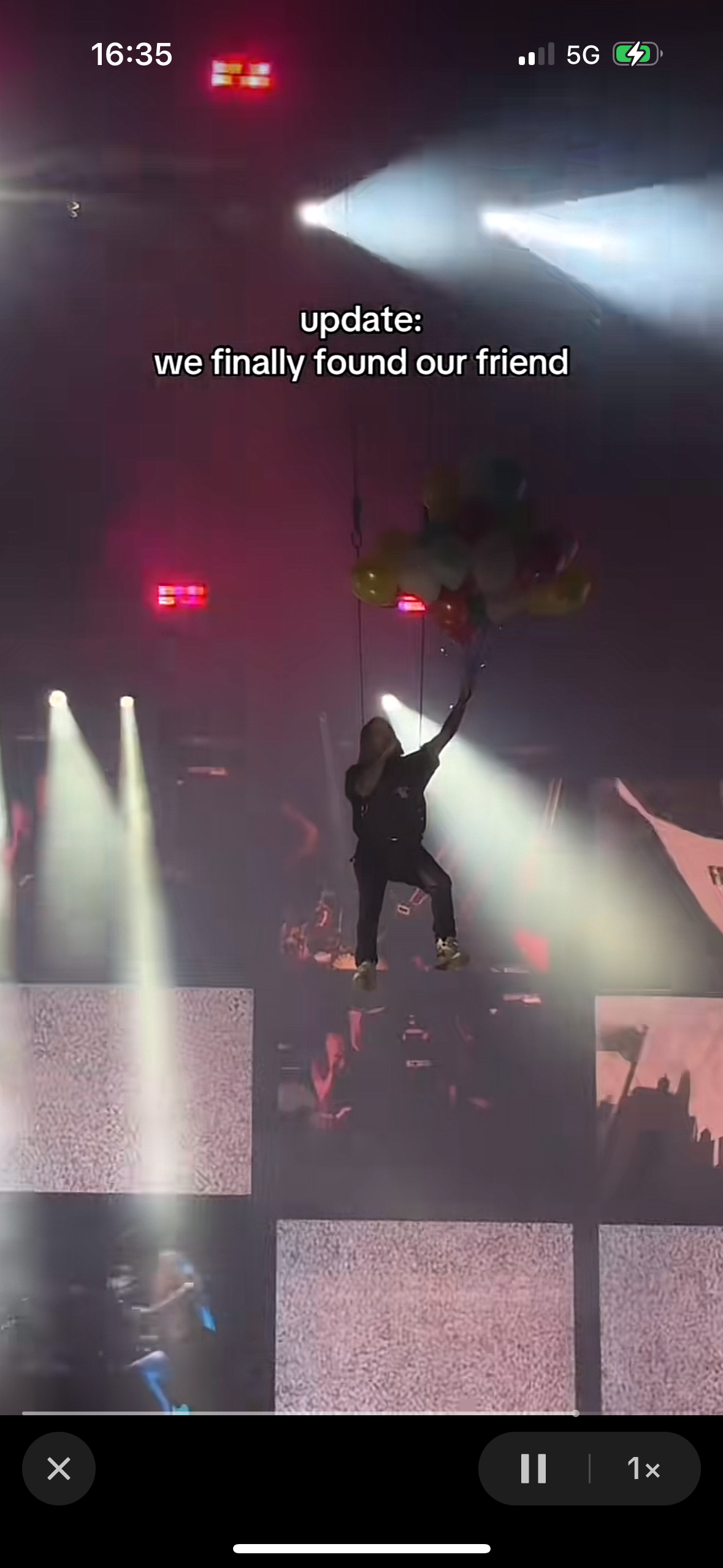 a screen recording of a live concert performance. the video shows a person hanging from the ceiling of a concert venue, with the caption "update: we finally found our friend."  the lights are shining brightly on the stage and the crowd is enjoying the show.