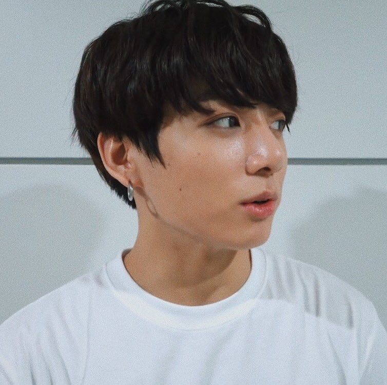 a closeup portrait of a young asian man with dark hair wearing a white tshirt. he's looking slightly to the right with his mouth slightly open as if he's about to speak. the background is a simple white wall. the lighting is soft and diffused, highlighting his clear skin.