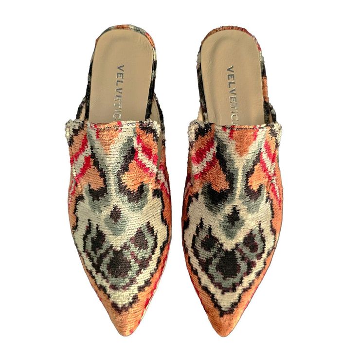 a pair of women's slippers,  pointed toe, with a floral pattern. the slippers are red, white, and have a gray pattern. the slippers are made of velvet. the slippers are on a white background.