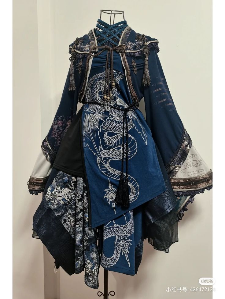 a full shot of a dark blue and black women's dress that features a dragon design.  the dress is layered with different fabrics and textures, and has intricate details and embellishments, suggesting a gothic lolita, steampunk or other fantasy style.  the dress is displayed on a mannequin against a white backdrop.