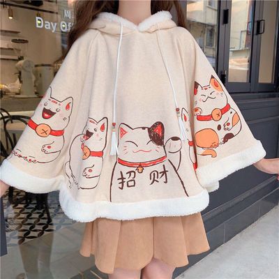 a young woman wearing a cute, oversized hoodie with a cat print. the hoodie is made of soft, fleece material and has a fluffy white collar. the cat print is in a kawaii style and is surrounded by a red border. the woman is wearing a skirt and is smiling. she appears to be comfortable and happy. the overall look is casual and comfortable, with a focus on the cute and playful aspect.