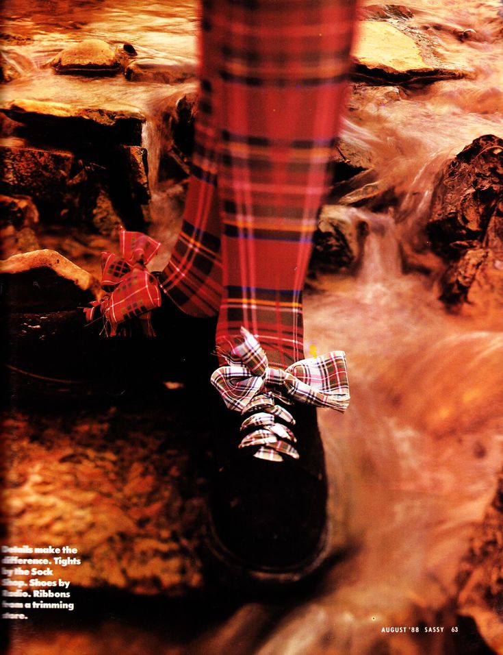 an image from an august 1988 issue of sassy magazine shows someone's legs and feet standing in a shallow waterfall. the person is wearing red plaid tights and black shoes with plaid ribbons tied on the laces. the caption in the magazine references where to get the tights, shoes and ribbons.