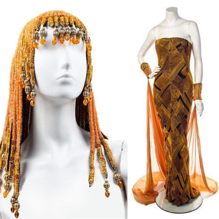 a strapless, fitted evening gown and beaded headpiece are displayed on mannequins. the gown is mainly orange and features black geometric patterns. sheer orange panels extend from the sides of the gown to the floor. matching orange beaded cuff bracelets adorn the mannequin's wrists. beside it, a mannequin head wears a long orange beaded headpiece, with ornate beaded details.