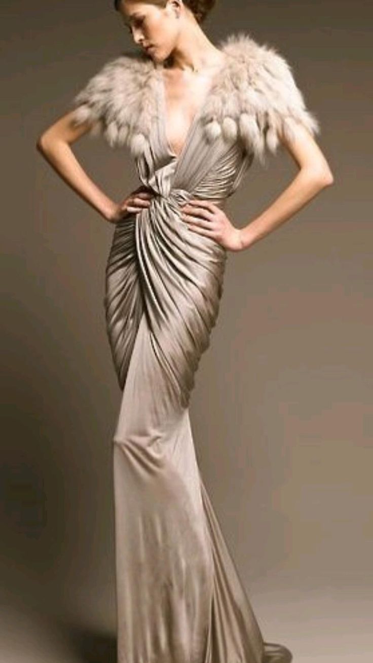 a glamorous model is wearing a stylish, formfitting dress with a  fur shawl and posing in a studio setting. she has her hair pulled back and is striking a confident pose, highlighting the beauty of the dress.
