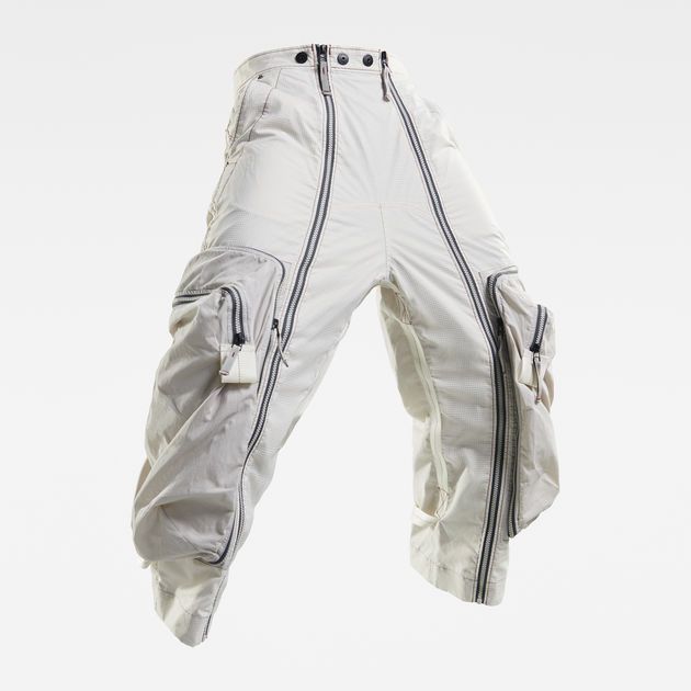 a pair of white cargo pants with zipper details. the pants are loosefitting and have multiple pockets, including two large cargo pockets on each leg. the pants also have zipper details down the sides of the legs. the pants are made by gstar raw and are perfect for casual streetwear.