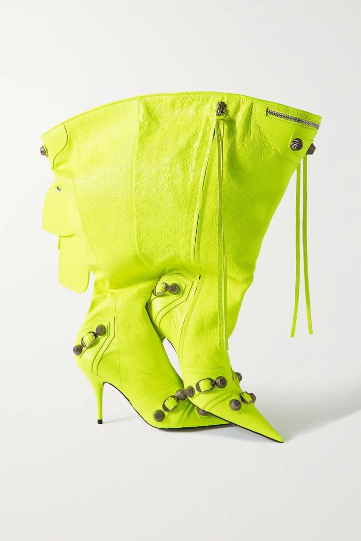 a pair of neon yellow leather, overtheknee boots are displayed against a white background. the boots have a pointed toe and high heels, and are studded with decorative metal accents. they feature a slouchy design at the top and a visible zipper closure.