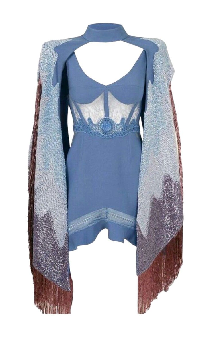 a kneelength blue dress is displayed on a white background, featuring a cutout neckline and a white lace panel in the bodice. it's accessorized with a decorative belt. a fringed cape drapes over the dress, transitioning from silver to brown.