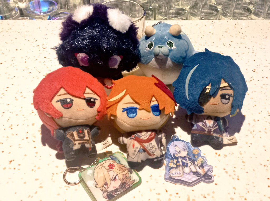 a collection of anime character plushies and keychains. the plushies are all different colors and feature a variety of designs. they are displayed on a table, and they appear to be part of a fan's collection.  the keychains are all acrylic charms with different characters.  these are the types of collectibles fans enjoy getting when they purchase merchandise.