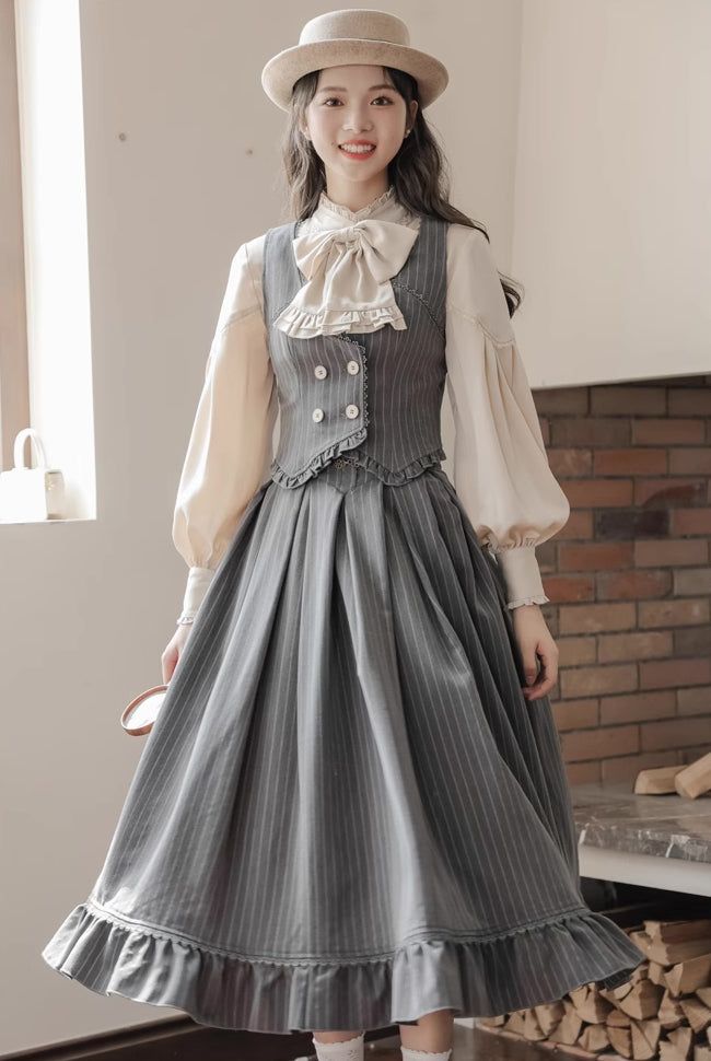 a young asian woman poses for a fashion shoot in a vintageinspired lolita dress. the dress features a grey pinstripe skirt with a ruffled hem and a matching waistcoat with a doublebreasted button closure. the model is also wearing a white blouse with puffed sleeves and a neck bow. she is accessorized with a brown fedora hat. the photo is taken indoors in a softly lit setting.