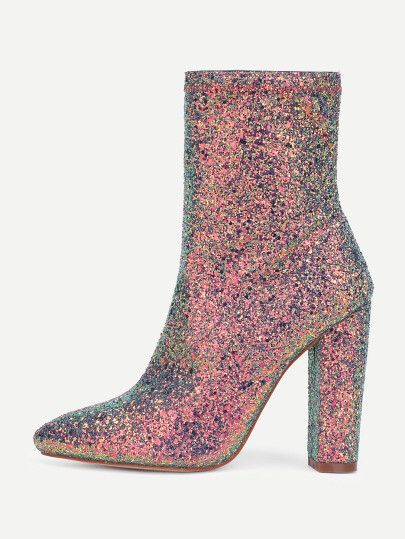 the image shows a single women's ankle boot with a pointed toe and a block heel. the boot is covered in iridescent glitter fabric in shades of pink, purple, and green. it's positioned on a white background, angled slightly to the side to showcase the design and heel. the style suggests a dressy or party occasion.