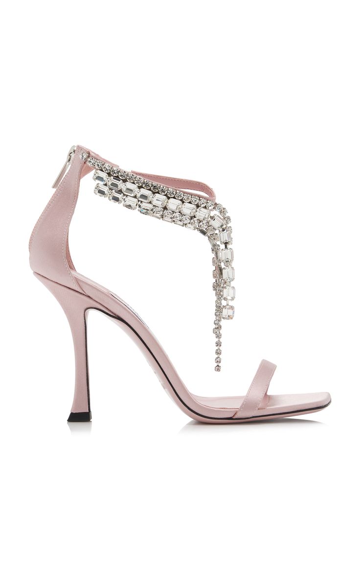 a pair of amina muaddi pink satin high heels with a square toe and crystal embellishment. the heels are embellished with a cascading fringe of crystals. the shoes are shown on a white background.