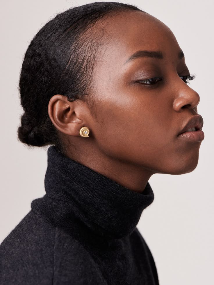 a profile portrait of an african american woman wearing a black turtleneck and gold earrings.