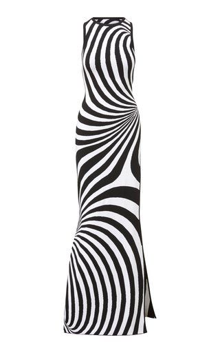 a black and white striped maxi dress is shown. the dress is sleeveless and has an optical illusion pattern. it is a bodycon style and has a slit on one side.