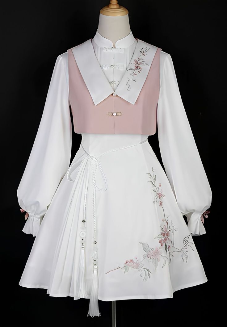 the image showcases a white and pink hanfu dress displayed on a mannequin. the dress features a white blouse with long, flowing sleeves, a delicate pink vest adorned with floral embroidery, and a matching white skirt with similar floral detailing. a white tassel hangs from the waist, adding to the overall elegance. the background is a neutral dark gray, allowing the intricate details of the outfit to stand out. the soft lighting creates a gentle and feminine ambiance.