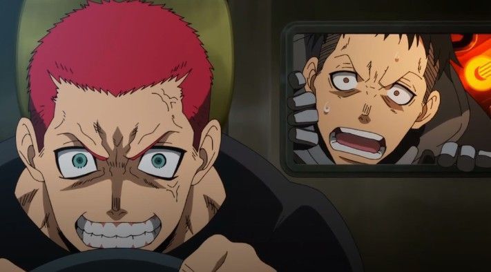 a man with red hair is looking at something offscreen. he has a wide smile with a lot of teeth showing. he is looking very angry and excited. behind him, there is a screen that shows another man with his mouth wide open.
