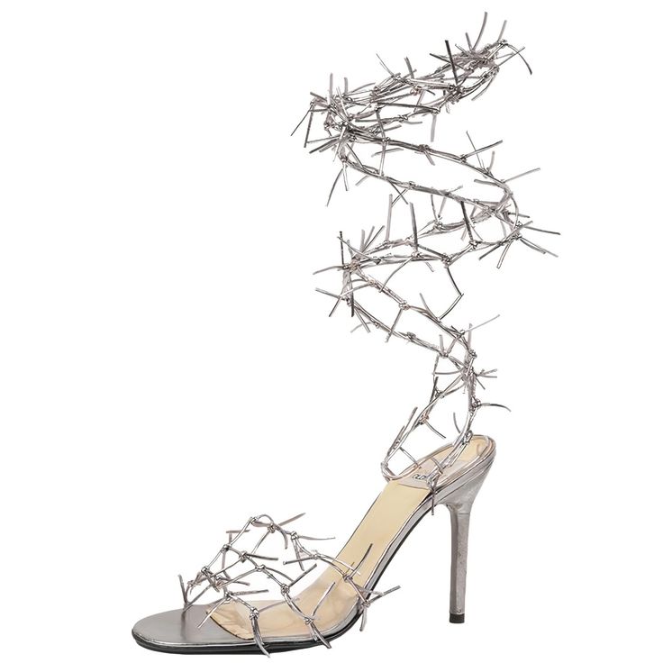 the image shows a pair of women's highheeled sandals with a unique design.  the sandals are silver or metallic in color and feature a series of thin, pointed metal pieces that resemble barbed wire or spikes wrapped around the ankle and extending onto the foot. the heel is stilettoshaped, and the sole appears to be clear or transparent. the overall style is avantgarde and eyecatching.