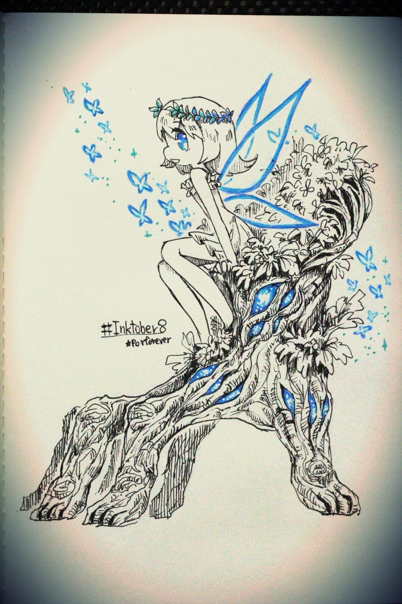 a black and white line drawing of a fairy with blue wings sitting on a tree trunk. the fairy has a crown of flowers on her head and is surrounded by small blue butterflies. the tree trunk is covered in small flowers and the fairy's wings are outlined in blue. the fairy's hair is long and flowing. the background is a white paper. the image is drawn with a black pen and ink. the image is drawn in a whimsical and ethereal style. the fairy is a symbol of magic and wonder.