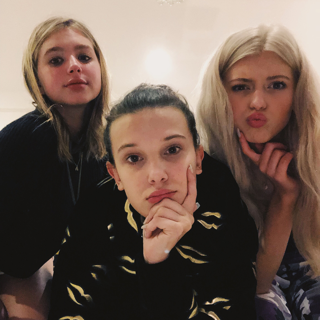 a selfie of three women with blonde hair. the woman in the center is wearing a black jacket with gold accents, the woman on the left is wearing a dark sweater and the woman on the right is wearing a blue and purple patterned top. they are all looking at the camera with various expressions.