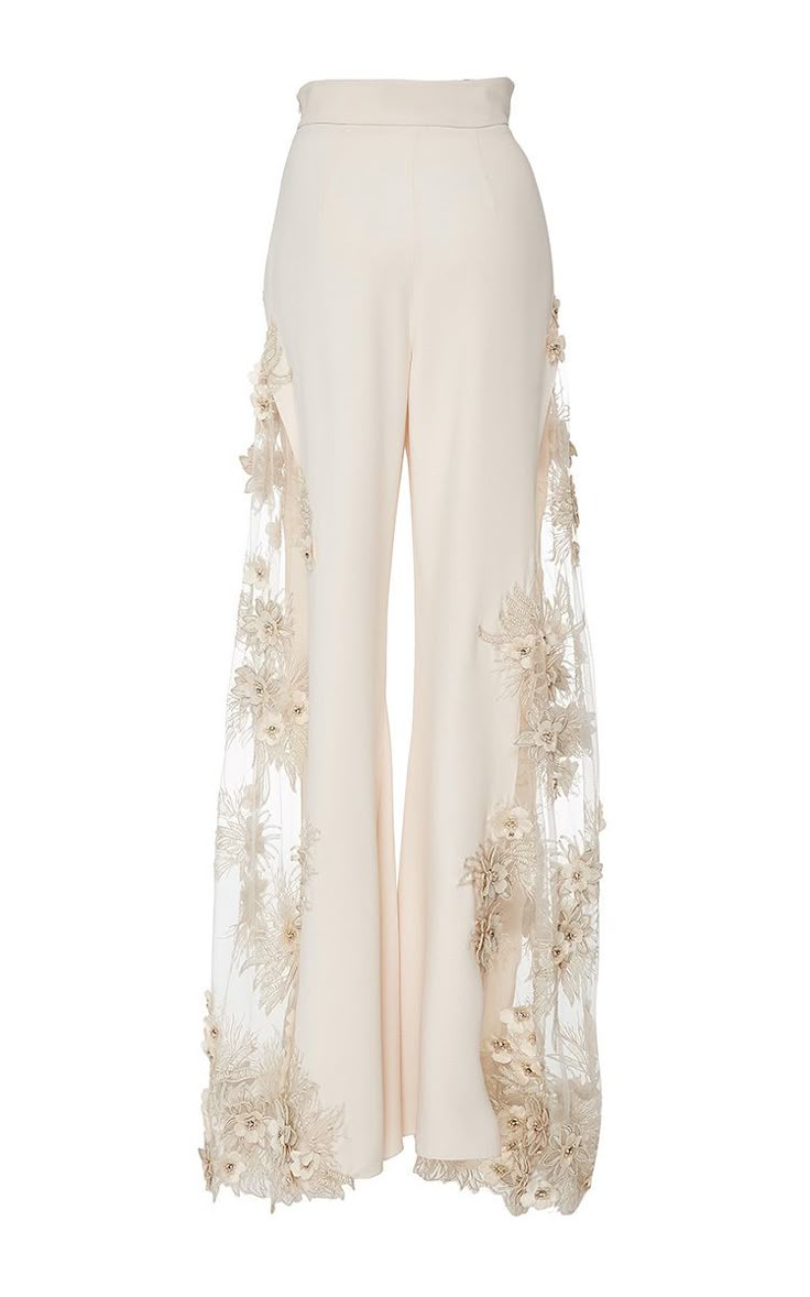 a pair of highwaisted, wideleg beige pants with floral appliques along the sides is displayed on a white background.