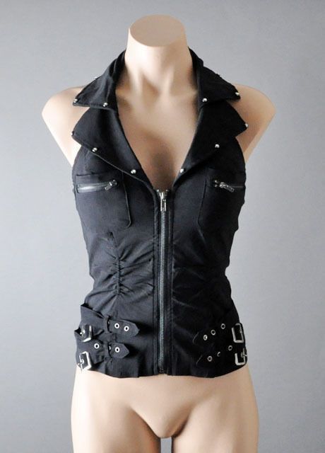 a woman is wearing a black sleeveless crop top with a zipper in the front. the top has a collar and is made of a soft material. the model has her arms by her sides. the background is a light gray wall.