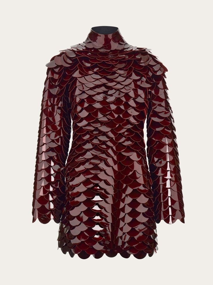 a glossy, red mini dress with long sleeves and a high neck is covered in scalelike embellishments.