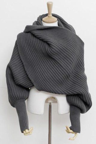 a gray knitted scarf wrapped around a mannequin's neck and shoulders. it's a chunky, oversized cowl neck scarf with a wrap style. it's a cozy and warm accessory perfect for fall and winter. the scarf is very stylish and chic.