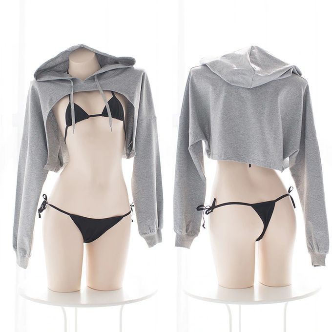 the image shows two mannequins, one facing forward and one facing backward, both wearing a grey cropped hoodie and a black bikini. the hoodie is styled to expose the bikini. the mannequins are standing on white pedestals against a white background. the overall style is suggestive and flirty.