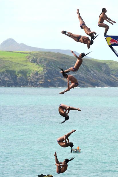 a series of cliff divers are captured in midair as they plunge into the ocean below. the divers are all in different positions and stages of their dives, creating a dynamic and exciting scene. the background is a beautiful landscape of mountains, cliffs, and water.  the image captures the beauty and danger of this extreme sport.
