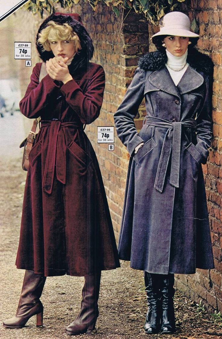 two women are posing against a brick wall, showcasing their long corduroy coats.  the woman on the left is wearing a burgundy hooded coat with a matching belt, while the woman on the right wears a dark gray belted coat with a faux fur collar. both women are wearing highheeled boots. the image is reminiscent of 1970s fashion photography, with a vintage aesthetic.  price tags are visible on the image, suggesting it may be from a catalogue or advertisement.