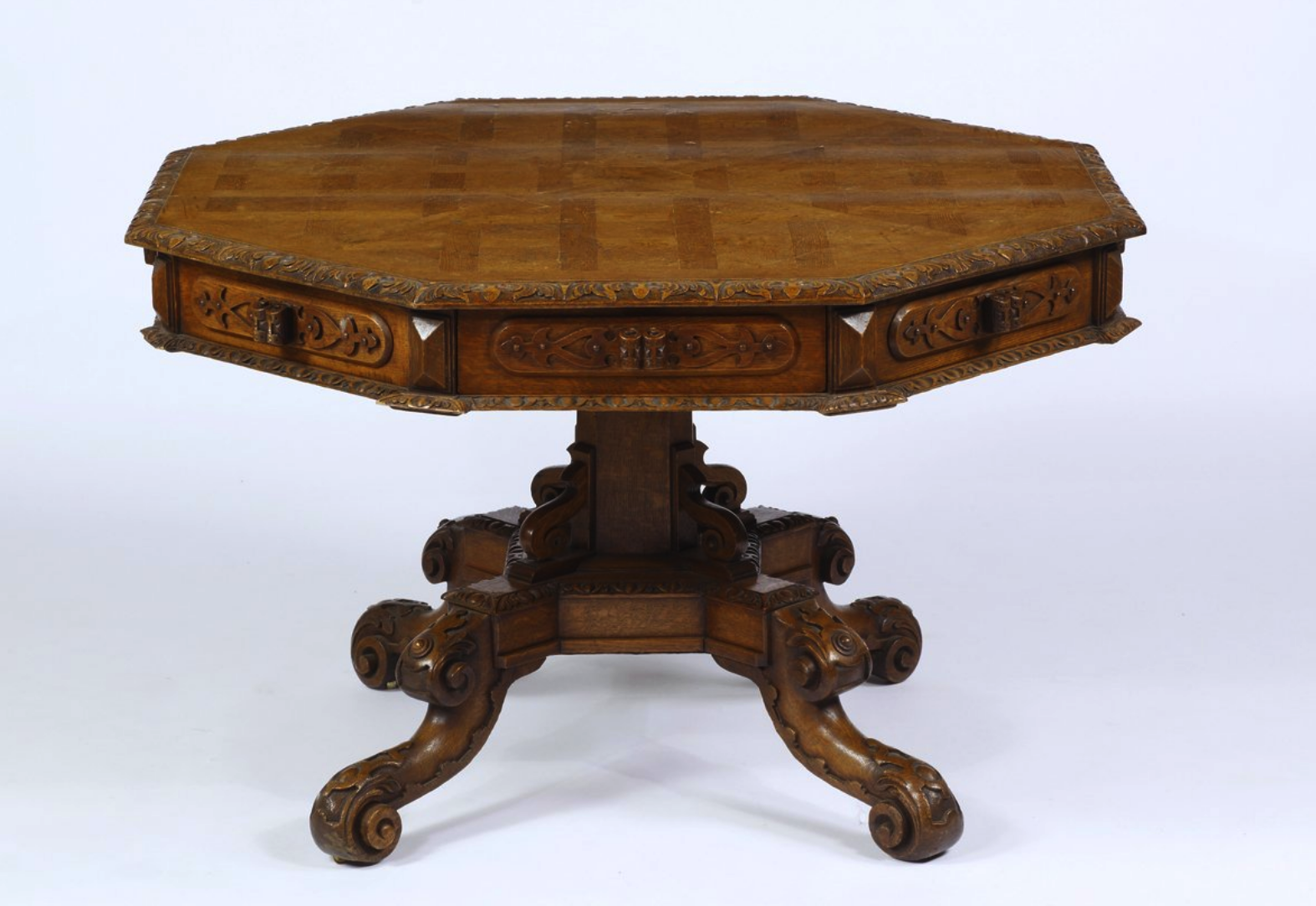 a close up of an ornate octagon table with intricate carved details, including an octagon top, four carved legs, and a carved base. the table is made of wood.
