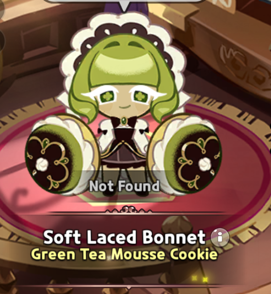the image shows a screenshot from the mobile game cookie run kingdom, featuring a character named green tea mousse cookie wearing a soft laced bonnet costume. the character is positioned on a red platform, and the words "soft laced bonnet" and "green tea mousse cookie" are displayed along with a small information icon. the character is in the center, wearing a green wig, a white lace bonnet, and a brown dress.