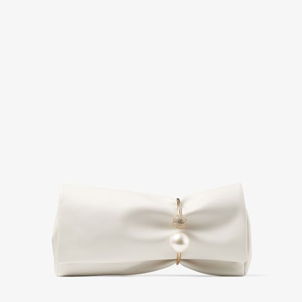 a white clutch with a gold ring that has a pearl and a jeweled circle on it.