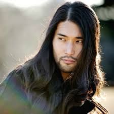 a portrait of an asian man with long black hair and a beard looking off to the side.