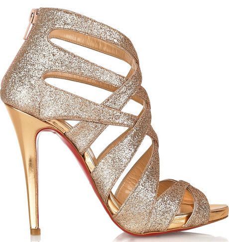 the image shows a pair of elegant gold glitter high heel sandals.  the shoes are opentoed with crisscross straps creating a cagelike effect over the foot. the heels are stilettos, and the soles are visible red (likely a signature of a designer brand). the overall appearance is glamorous and suitable for special occasions.