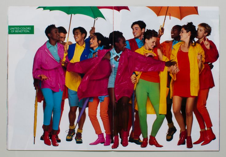 an advertisement for united colors of benetton featuring a diverse group of young people in brightly colored clothing holding umbrellas. the image is divided in the middle, likely a magazine spread. the people are wearing various colors such as pink, blue, yellow, green, orange, and red. the umbrellas are also different colors. the image conveys a sense of unity, diversity, and youthful energy.