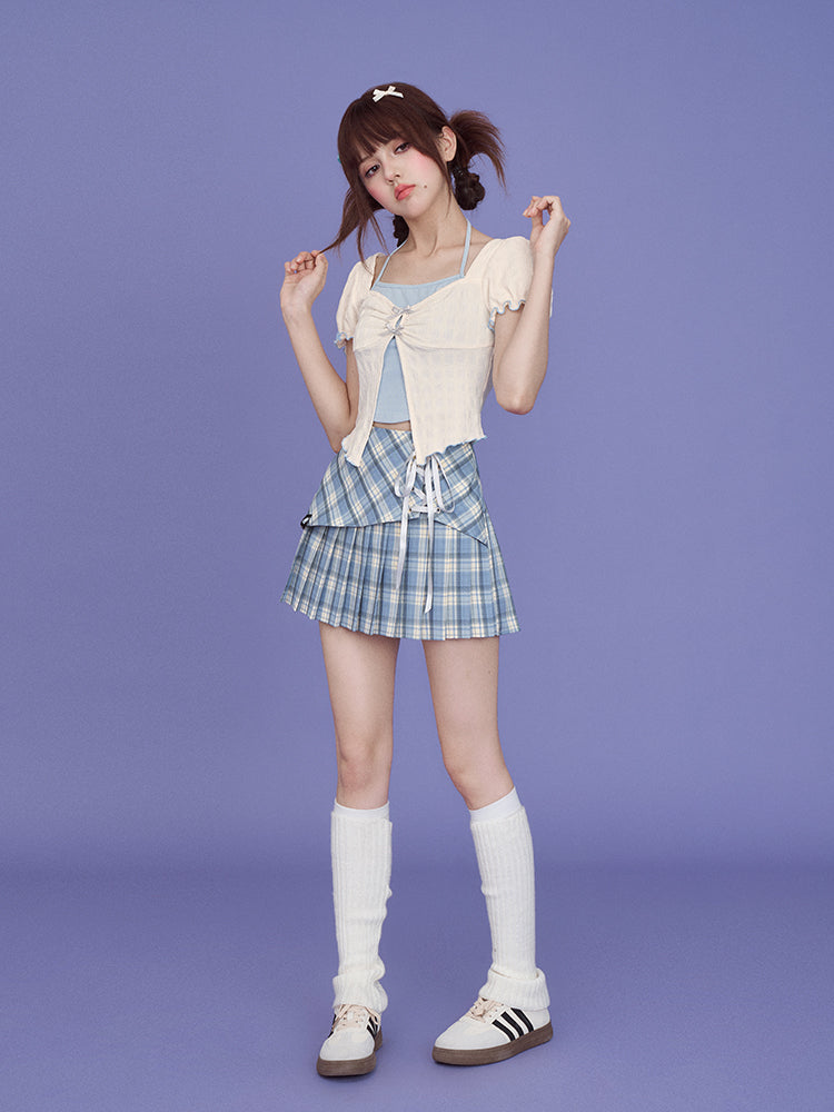 a fullbody shot of a young asian woman posing against a solid purple background. she is wearing a creamcolored crop top with a lacedup front and a light blue pleated plaid mini skirt.  her accessories include white kneehigh socks, black and white sneakers, and small hair clips. she has her hair styled in two pigtails. the overall style is cute and trendy. the image is welllit and professionally shot, likely for a fashion catalog or editorial.