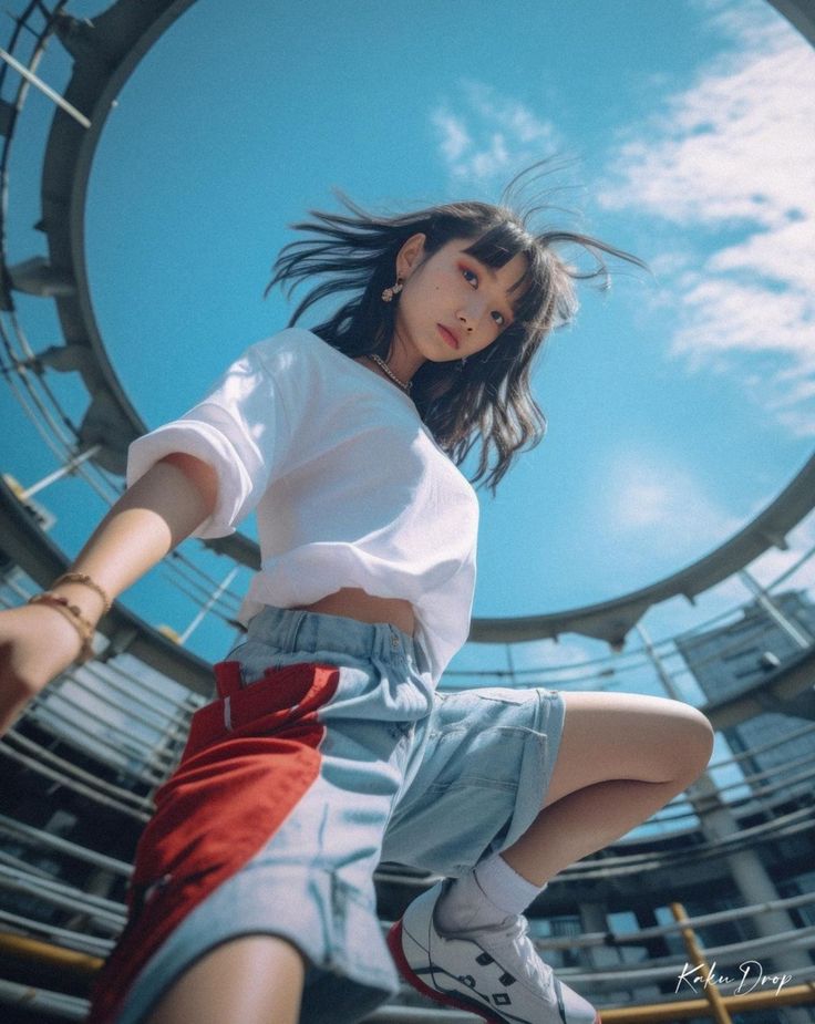 a young woman in stylish streetwear poses on a rooftop with a lowangle shot capturing her against a bright blue sky. the circular opening in the rooftop frames the sky, creating a unique composition. she wears a white cropped tshirt, denim shorts with red and white panels, white sneakers, and has a confident, youthful energy.