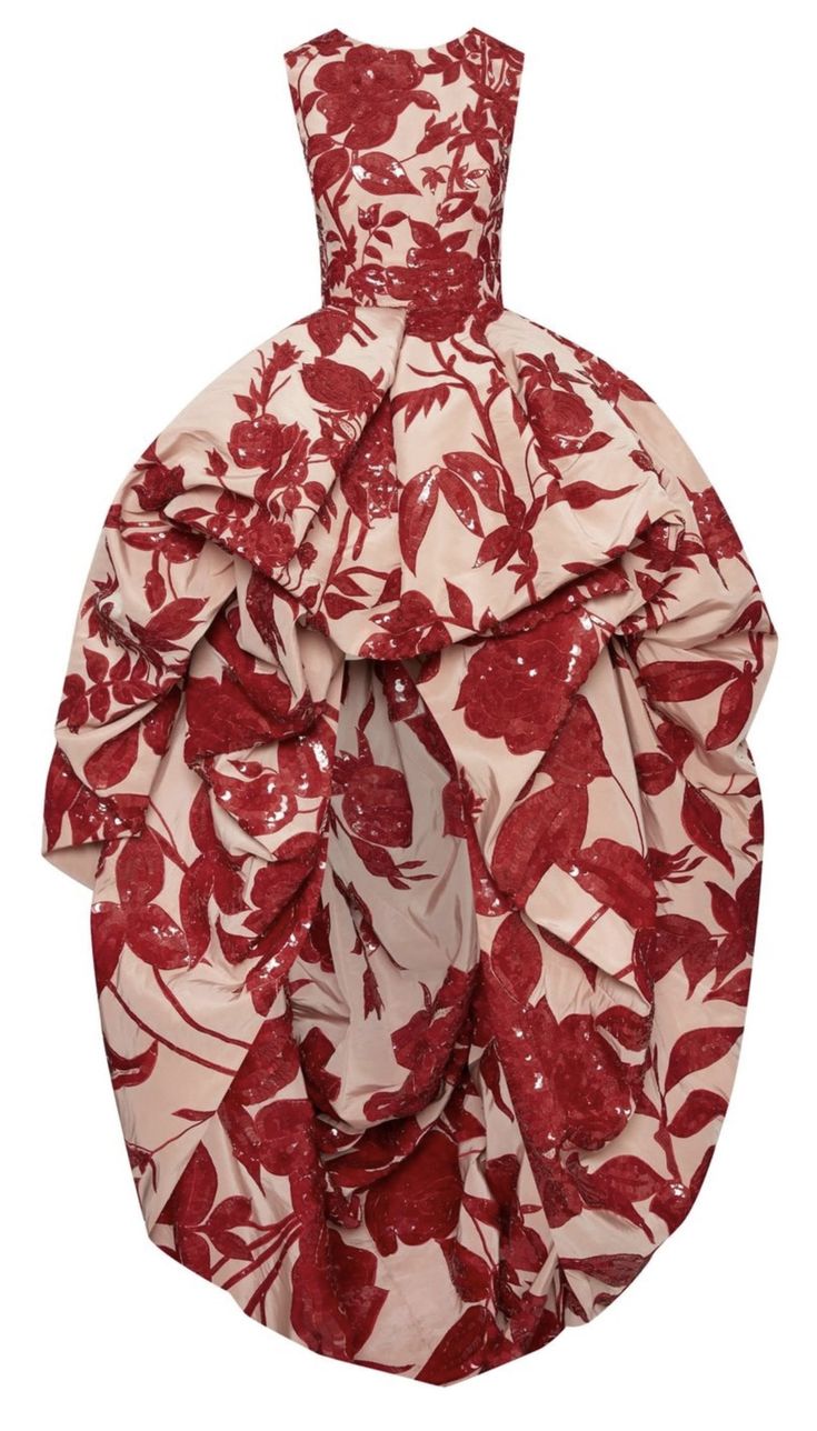 a couture dress with a red floral print on a beige background, featuring a sleeveless design and a voluminous, asymmetrical hemline, creating a statement piece.