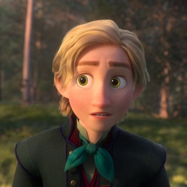 a closeup shot of ryder from disney's frozen ii. he is a young blondhaired boy with a concerned or thoughtful expression on his face. he is wearing a dark green jacket with gold detailing and a teal necktie. the background is softly blurred, showing a sunlit forest setting. the image appears to be a still from the animated film.