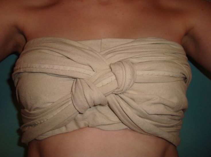 the image shows a closeup view of a woman's upper body from the chest up. she is wearing a strapless top made from a beige or tancolored fabric. the fabric is simply wrapped and knotted around her chest to form a rudimentary top. the fabric appears soft and somewhat drapey. the woman's skin is visible where the fabric doesn't fully cover her. the image appears to be a casual or informal shot, possibly showcasing a homemade or diy garment.