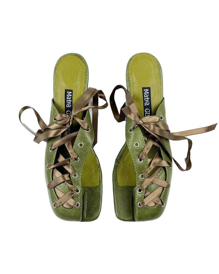 a pair of olive green slipon shoes with brown laces on a white background. the laces are tied at the top of the shoes. the shoes have a rounded toe and a flat sole. the brand name, "matea g." is visible on the insole of both shoes.