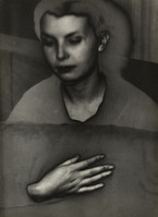 the image is a black and white, closeup portrait of a woman.  her face is partially obscured, and her expression is serious and contemplative. a hand is prominently featured in the lower portion of the image, resting on a surface. the overall mood is dark, mysterious, and somewhat surreal. the photograph appears vintage or has a vintage aesthetic, with a grainy texture.  the use of light and shadow creates a strong sense of depth and drama. the style suggests influence from surrealist or dadaist movements.