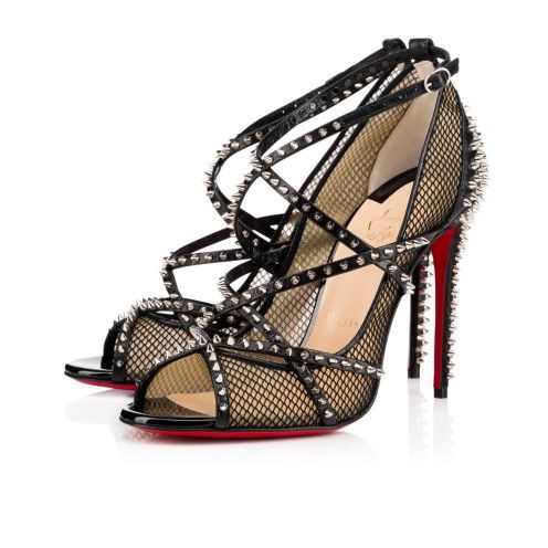 a pair of christian louboutin black mesh studded peeptoe heels are shown in this image. the shoes feature crisscross straps and are adorned with silver studs. the heels are high stilettos with the signature red soles. the shoes are positioned at an angle, with one shoe slightly in front of the other. the background is white.